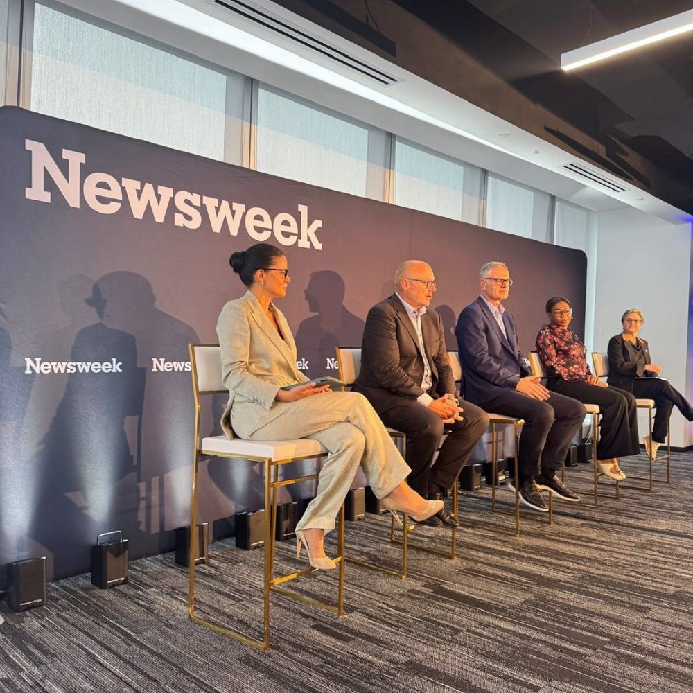 Five people sitting on a panel in front of a Newsweek banner