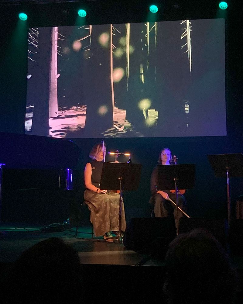 Musicians on stage in front of animated backdrop of trees