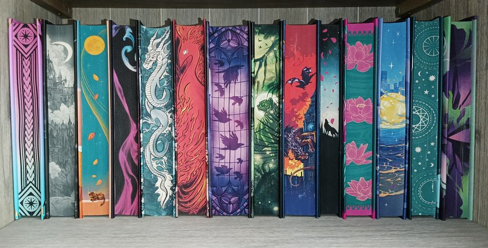 A row of special edition books:
Hammajang Luck - Mistress of Lies - Rewitched - A Tempest of Tea - Of Jade And Dragons - The Blood Phoenix - The Raven Scholar - Prince Without Sorrow - A Language of Dragons - Moonstone - Goddess Of The River - Watermoon - The Last Hour Between Worlds - Until We Shatter