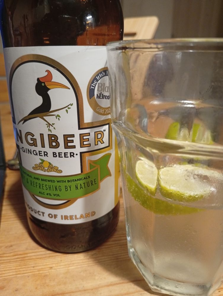 A bottle of zingibeer & a half full glass with lime slices & clear zingibeer yum yum 
