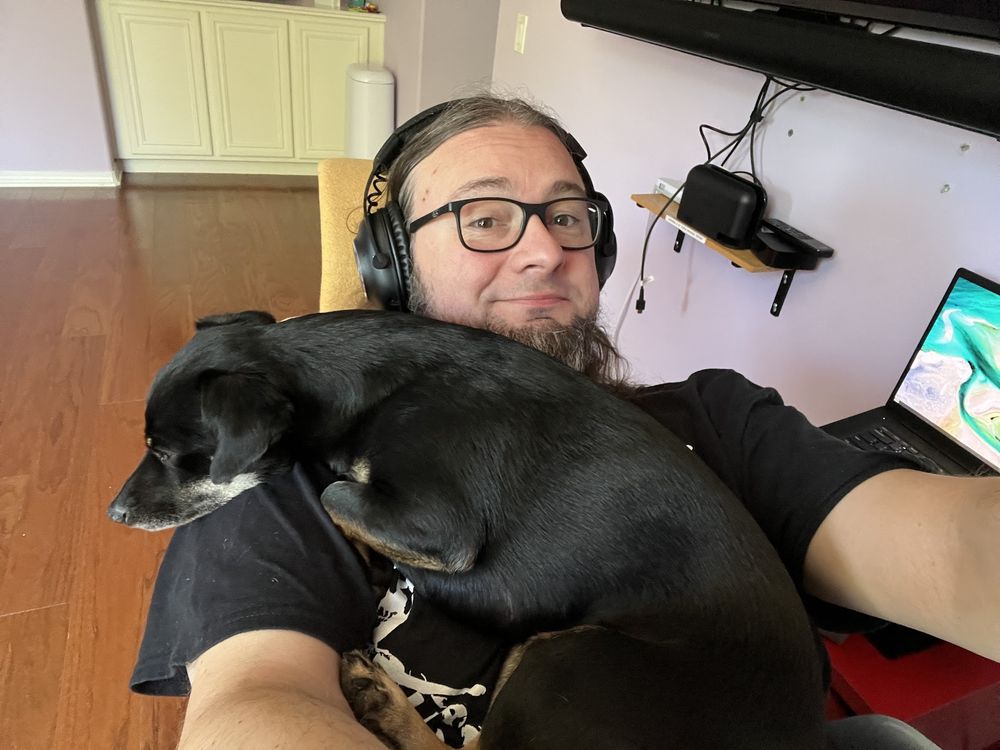 A picture of Yuna, our black mutt, chilling on my chest as I recline in my office chair. 