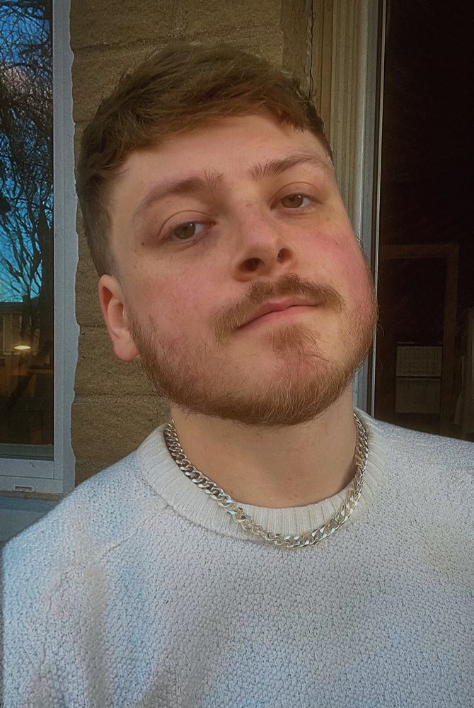 Selfie of a man wearing a white sweater with a silver chain