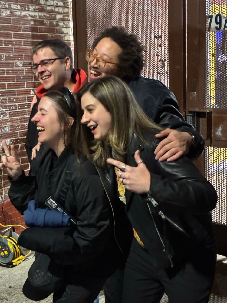 a photo taken from the side of myself, severin, stephen, and lelia outside the hookah-slash-sports bar in atlanta that we found after ditching the buildkite/honeycomb/pulumi party, all smiling for a photographer off-screen