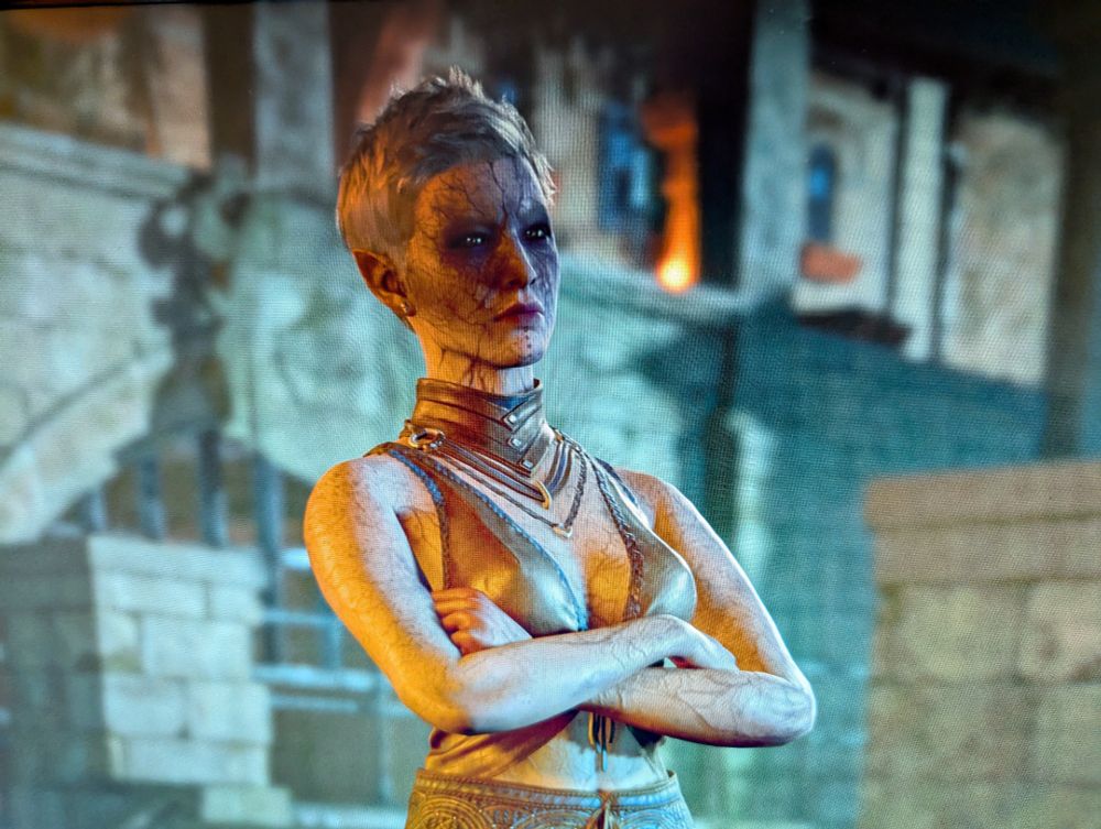 a picture of a baldur's gate 3 character, who is half drow and partial illithid, with crossed arms, sporting a pixie grey haircut and deep purple veins that are very visible throughout her face and body, while wearing a leather bikini top and slacks, great tits