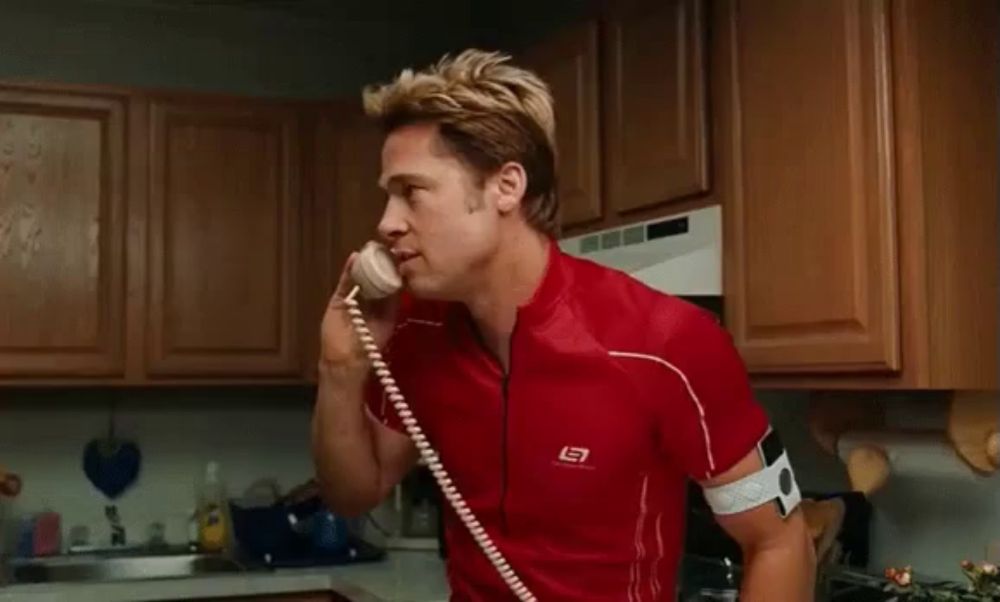 a man in a red shirt is talking on a telephone .