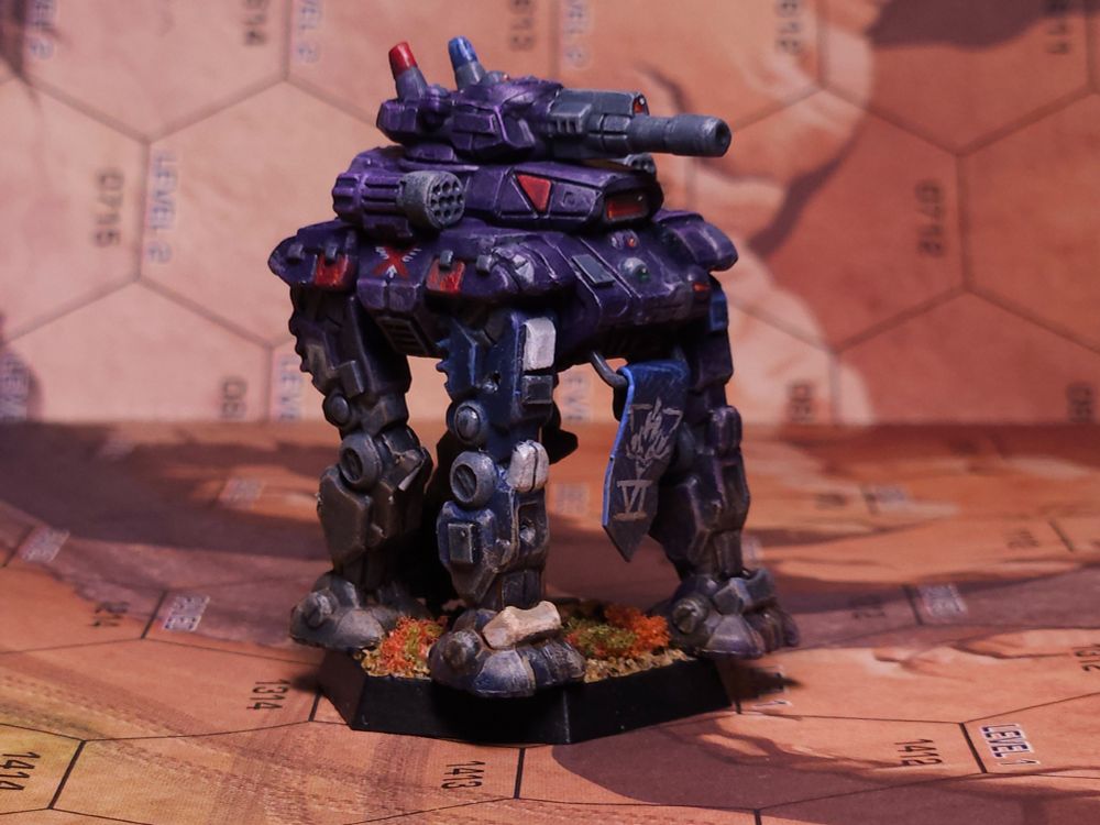 A Goliath assault battlemech. The main body and some of the legs are painted purple with blue and red accents, the color scheme of the Marik Militia, but the Free Worlds League eagle has been crossed out. The right foreleg is painted the blue and white of the Marian Hegemony VI Legio. A blue banner with the roman number VI and a Marian insignia hangs between the mech's forelegs