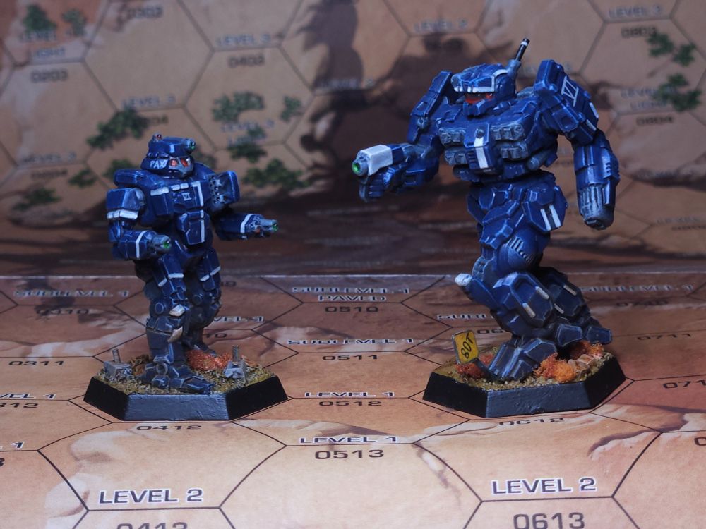 A Whitworth medium battlemech and a Charger assault battlemech. The mechs are painted blue, with white accents, the color scheme of the Marian Hegemony's VI Legio. The Charger has been altered to represent the 2A2 varianr, with rocket launchers on the torso and arms