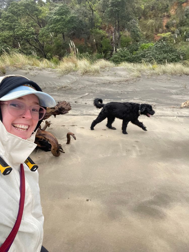 Selfie of me walking in a raincoat with Gus in the background walking alongside. I’m grinning at the camera. 