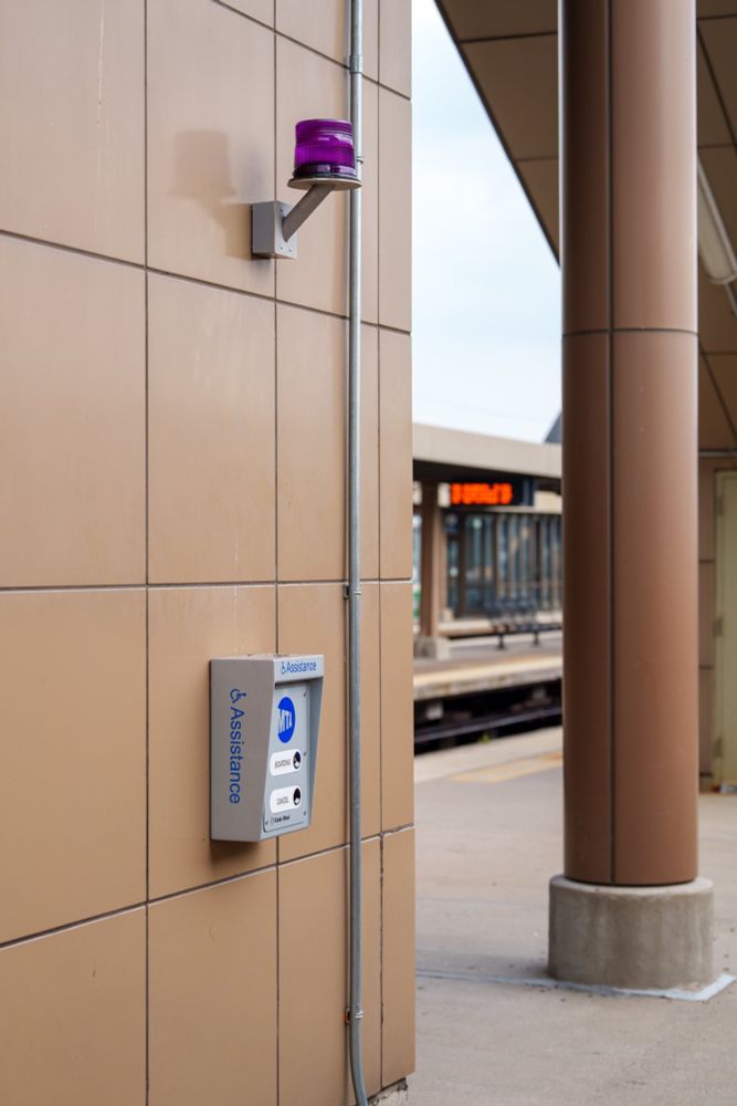 The boarding assistance button on a wall of Croton-Harmon station during the daytime. 