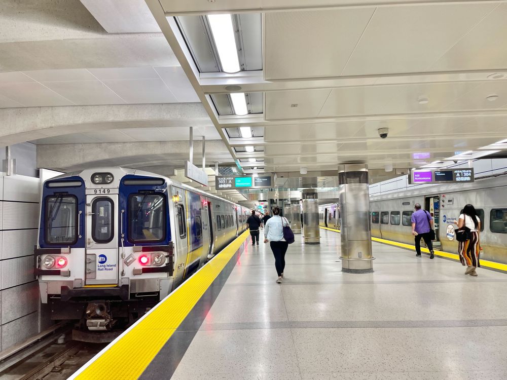 Customers walking along the Grand Central Madison platform, with two LIRR trains stationed.