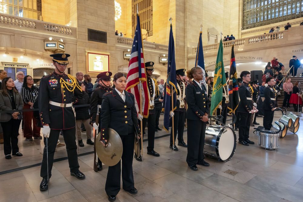 A group of Metro-North employees posed while carrying flags and standing beside their instruments at Grand Central.
