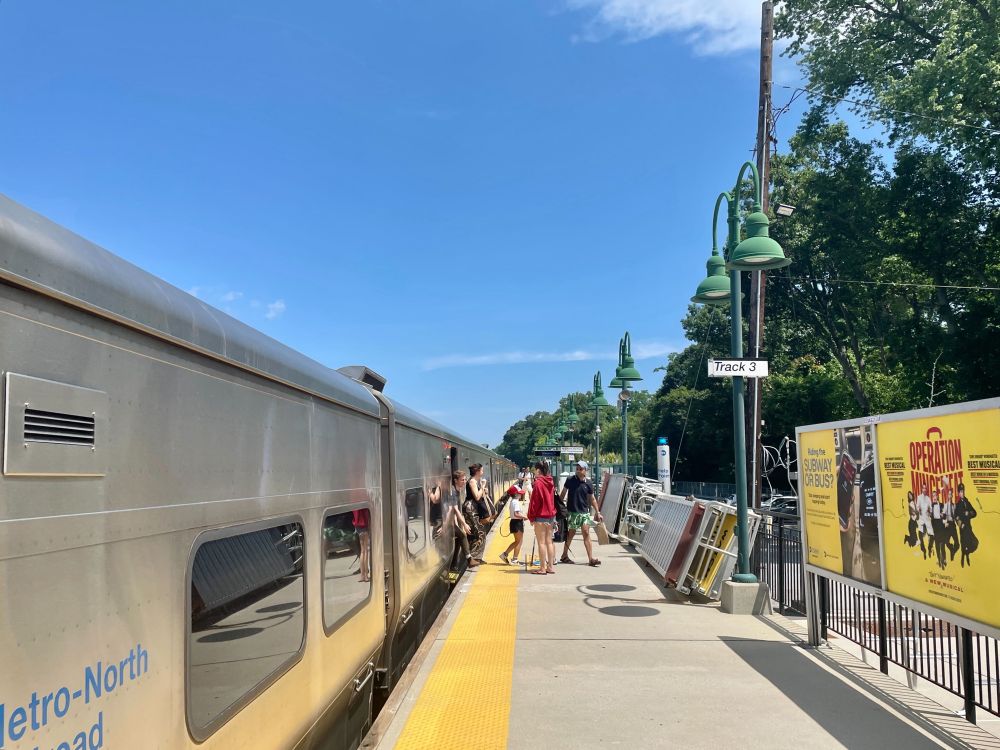 People exiting a Metro-North train on a sunny day.