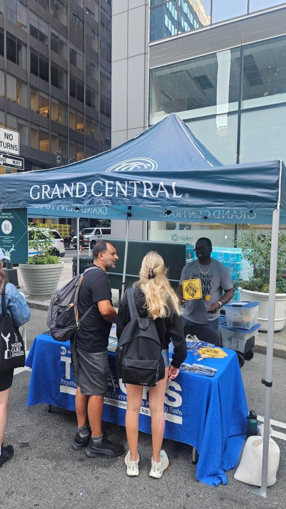 Metro-North staff interacting with people at the TRACKS table, containing brochure and other TRACKS safety merch, at Summer Streets.