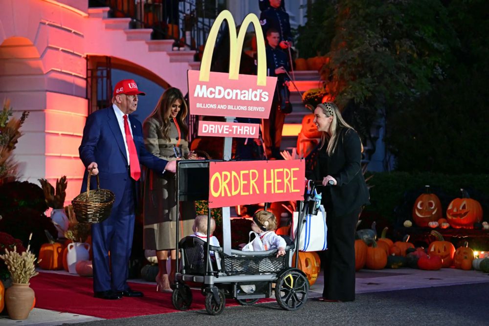 The Trumps at the White House Halloween event on Oct 30, 2025. They are standing next to a McDonald's sign.
