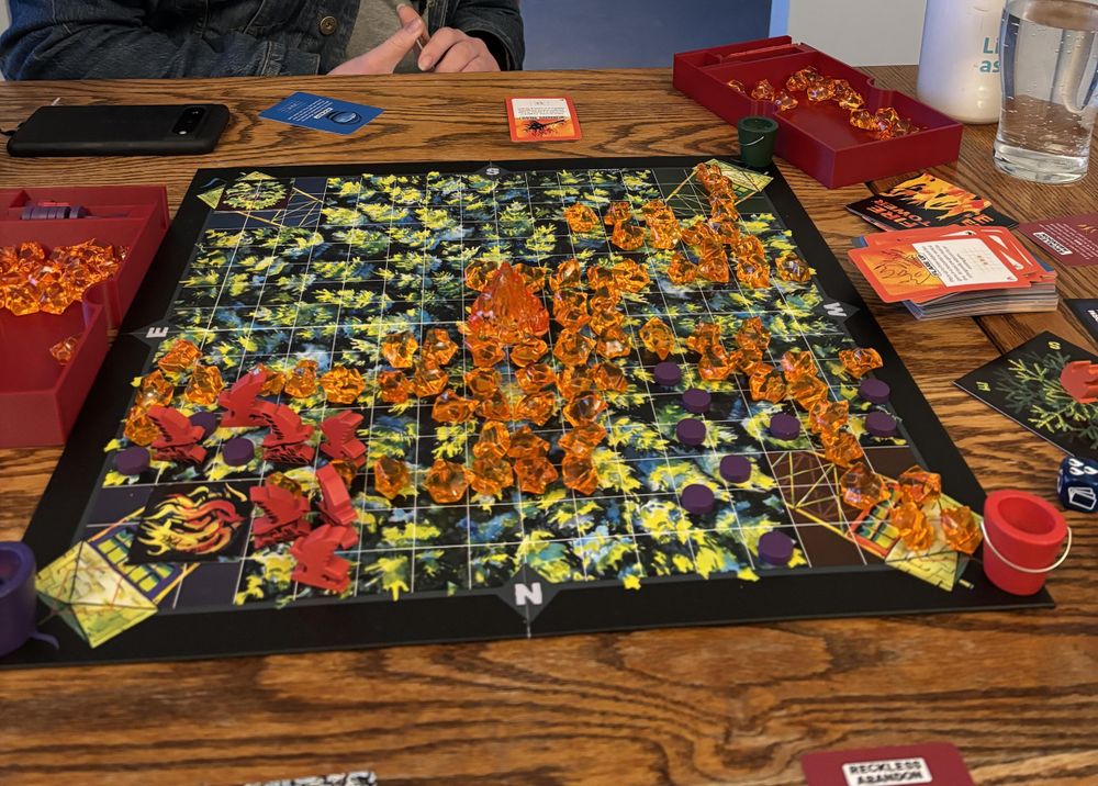 board game set up with little flames on squares and stacks of cards
