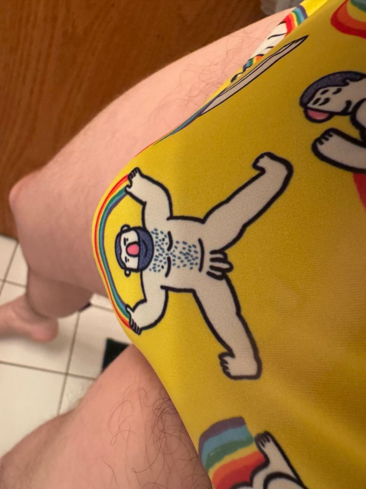 Close up of a yellow speedo featuring a drawing of a hairy naked man holding a rainbow