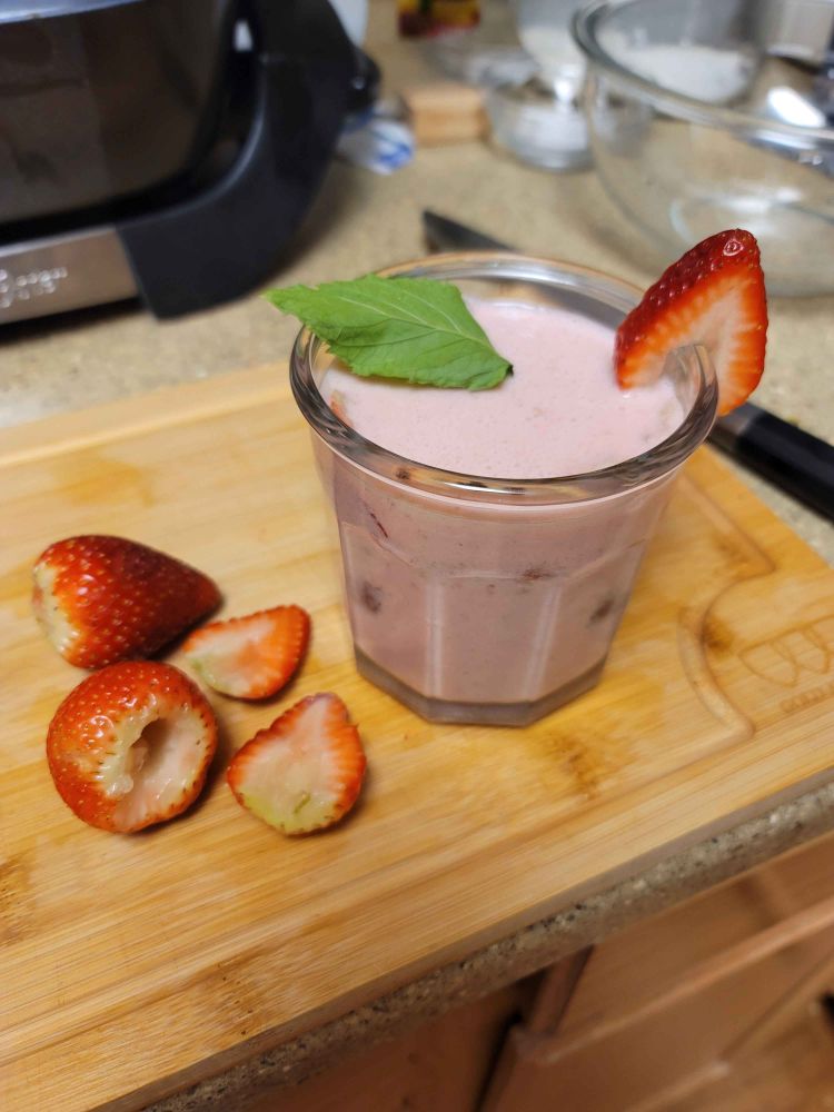A glass of strawberry agua fresca, garnished with strawberry slices and mint leaves