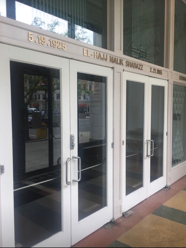 The front doors to the former Audubon Ballroom. Above the glass doors are gold letters with the epitaph of Malcolm X.