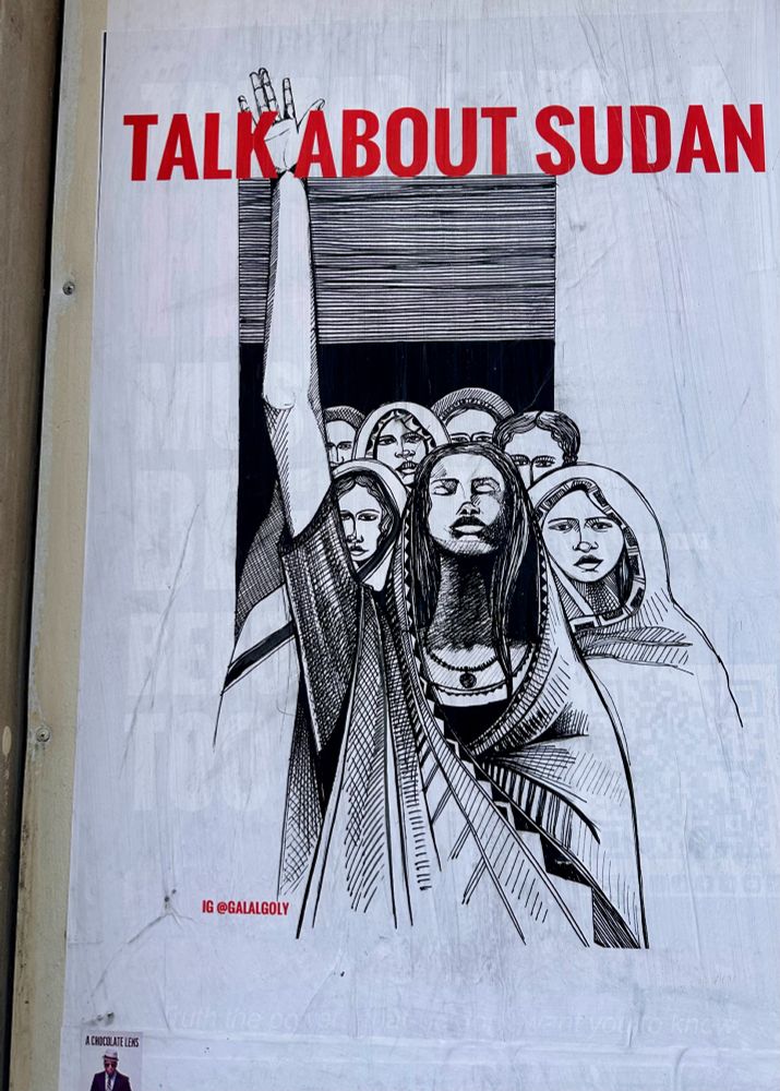 A white wheatpasted poster of Sudanese women the one in the front has her right arm up.