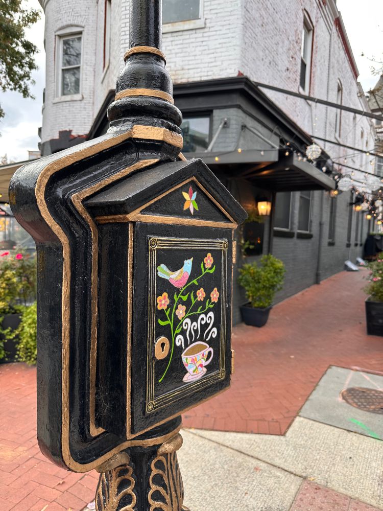 A restaurant in the background. A former police callbox painted black and gold in the foreground.
