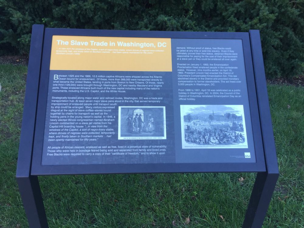 A table-top historic marker with text and two drawings depicting the traffic of enslaved Black people in Washington, D.C.