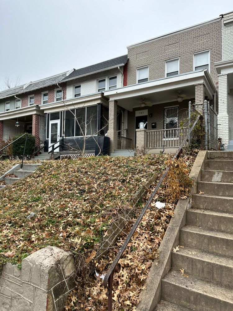 A row of houses, attached on either side to neighboring homes.  They sit on a slight hill and have small front yards.