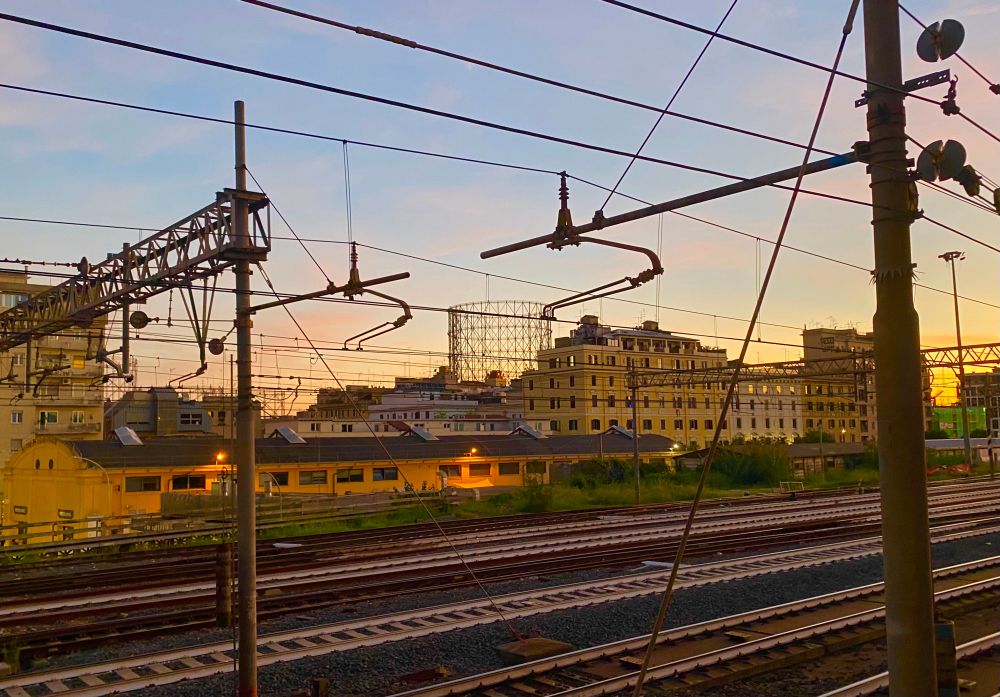 The skeletal silhouette of a gasometer, across the railway tracks in Ostiense, at dusk.