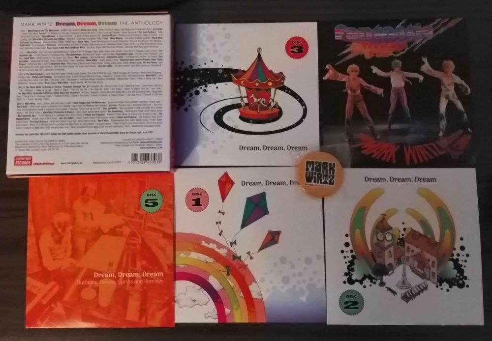 spread of boxset contents: inner sleeves, booklet, badge