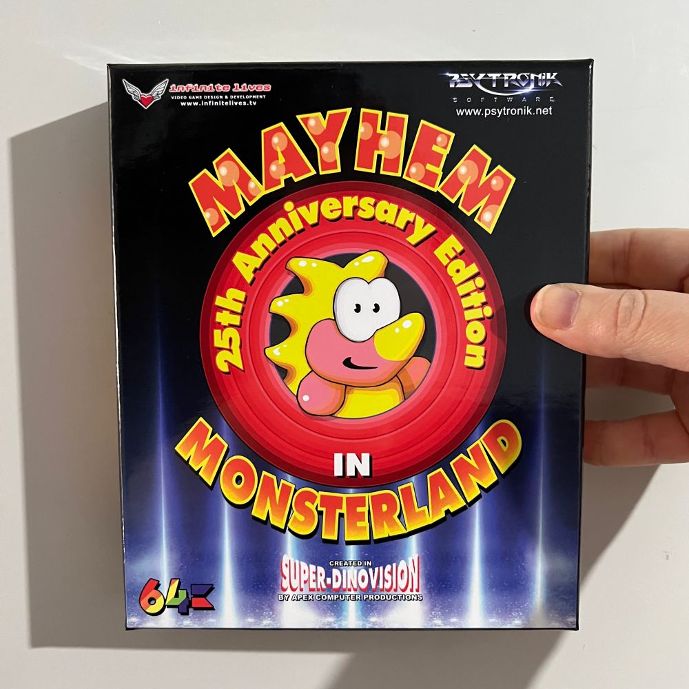 Holing up a boxed copy of the “Mayhem in Monsterland 25th Anniversary Edition” for the C64.

The cover illustration features the titular Mayhem (a yellow, Dino creature with a nose horn, and pink hands/face) popping out of a thing like the opening to the Looney Tunes cartoons, with the title surrounding it.