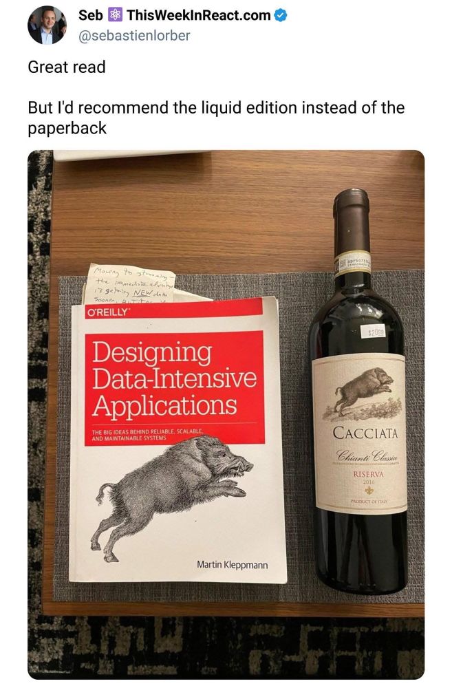 A book titled "Designing Data-Intensive Applications" by Martin Kleppmann next to a bottle of wine. Source https://x.com/sebastienlorber/status/1950142516872782186 