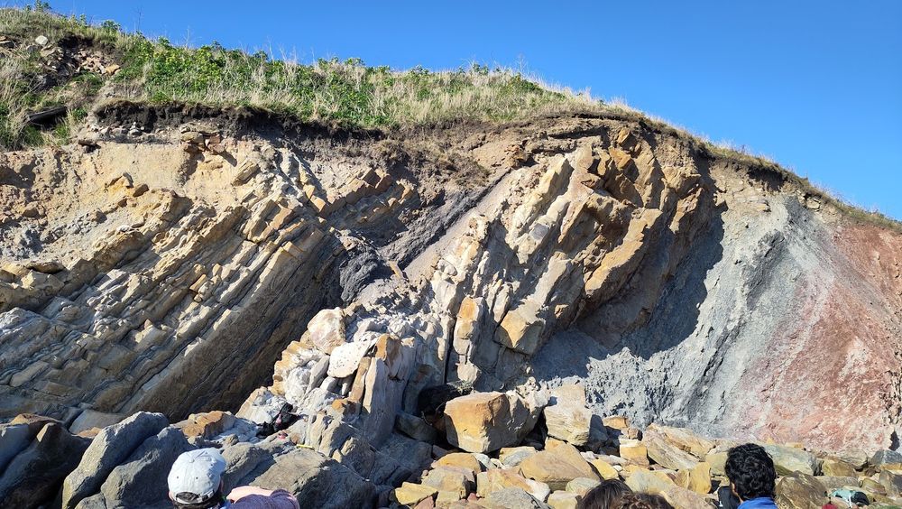 Blue skym then some lovely rocks - on the right, red through to grey, pretty poorly bedded sediments, and then in the middle, yellow, coraser grained, thick, well bedded rocks with discontinuous channels. To the left of this we have another finer grained bed, and then more sands. 