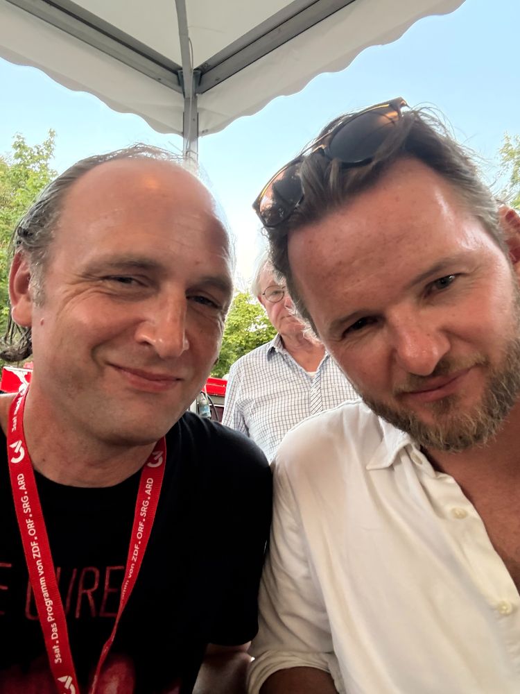 Autor Sebastian Stuertz im THE CURE T-Shirt und Verleger/Autor Tom Müller vom TROPEN Verlag lächeln beseelt in die Kamera