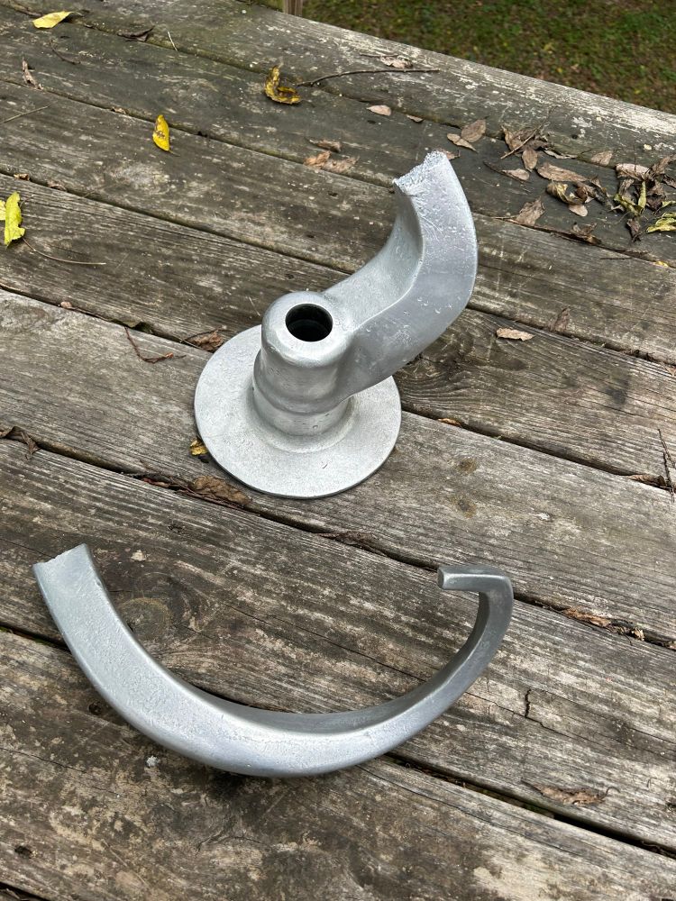 A large dough hook that is fractured leaving only about a quarter of the hook arm attached to the base 