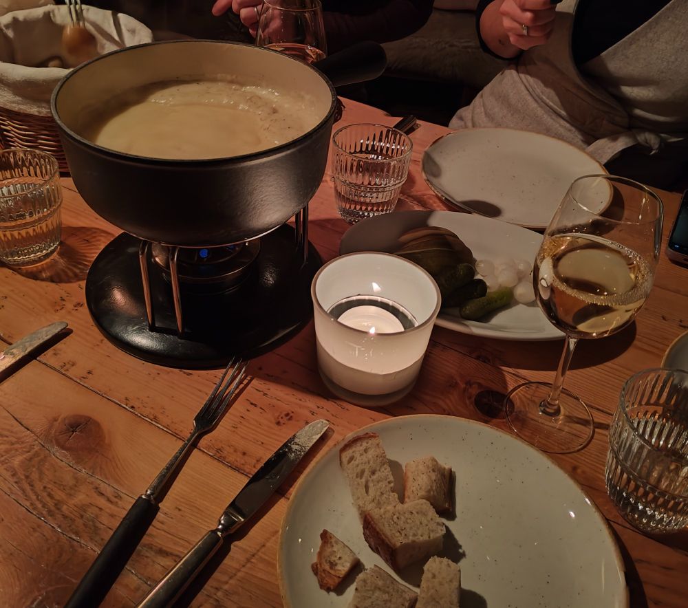 Image of a pot of fondue. There was bread, pickles, potatoes (not shown) and pear (hidden behind a candle) to dip in! 