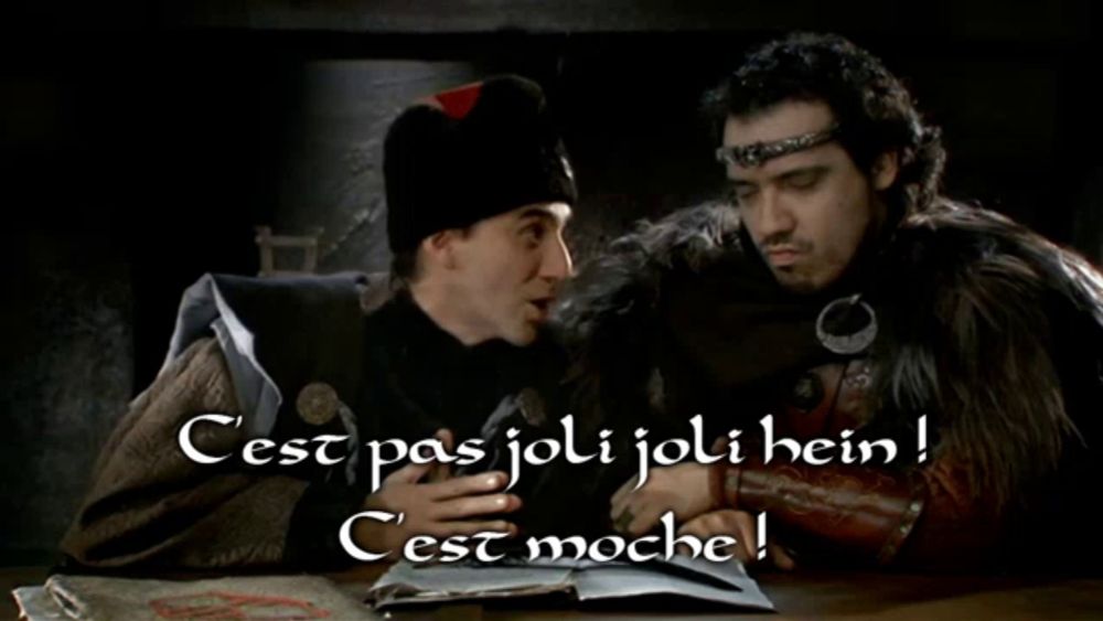 two men are sitting at a table with the words cest pas joli joli hein on the bottom