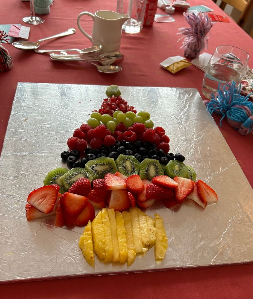 Diffrent fruit in the shape of a Christmas tree. Pineapple, strawberries, kiwi, blueberries, raspberries, grapes, pomegranate, kiwi (for the star)