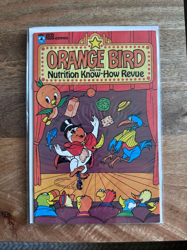 A comic book where a bird with an orange for a head flies above a white magician bird juggling food for an audience.