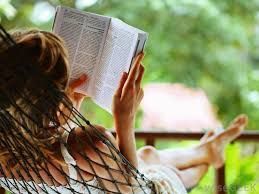 Person reading book while lying in hammock