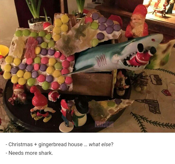 Et pepperkakehus hvor en hai kommer opp ut av taket og har en nisse i gapet. Tekst under bildet: «- Christmas + gingerbread house… what else? - Needs more shark.» 