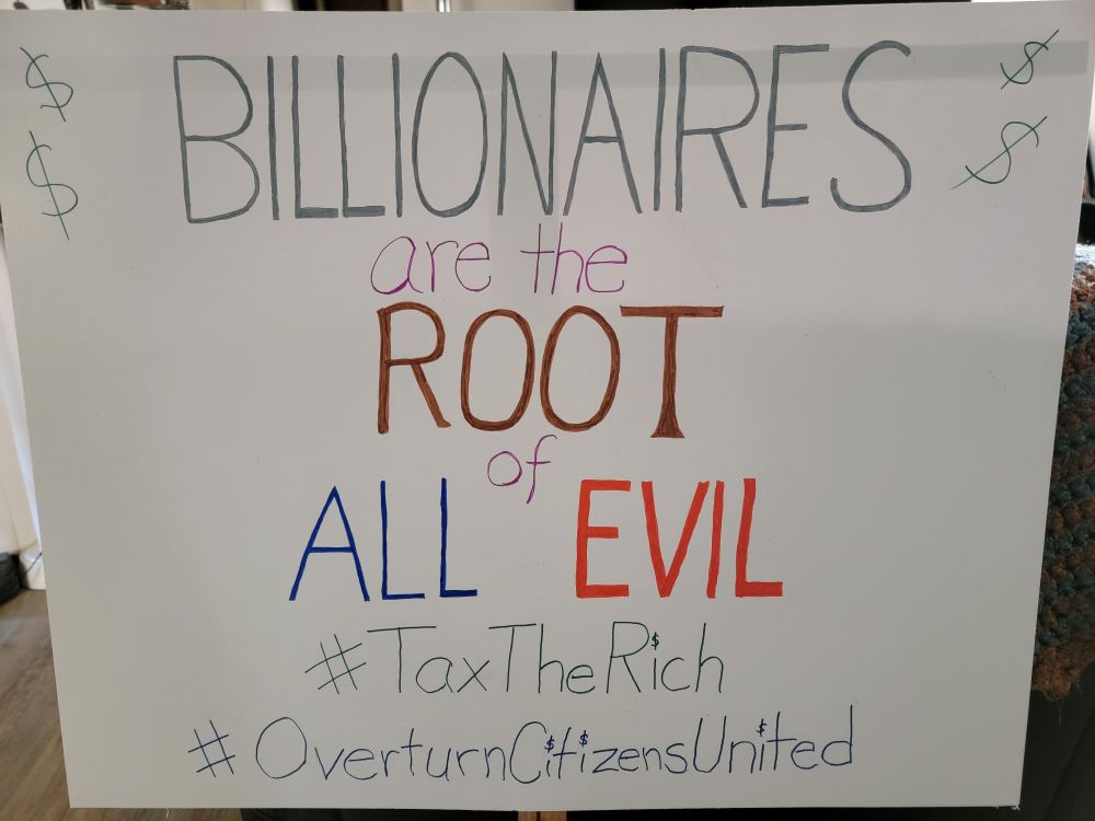 Protest sign reading BILLIONAIRES are the ROOT of ALL EVIL.