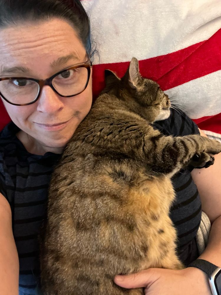 A cute polydactyl tabby cat laying across the chest of a lady in glasses (me) taking a selfie from above. 