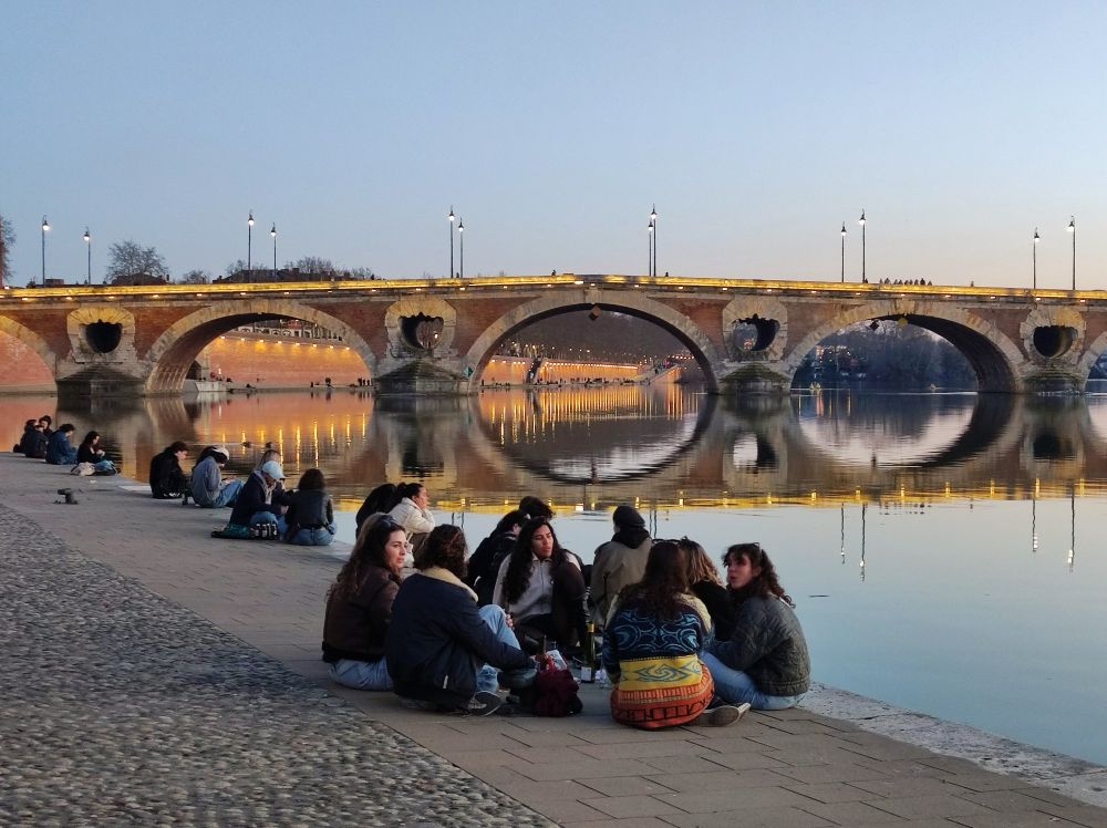 Toulouse, groupe assis en rond au bord de la Garonne devant le Pont Neuf