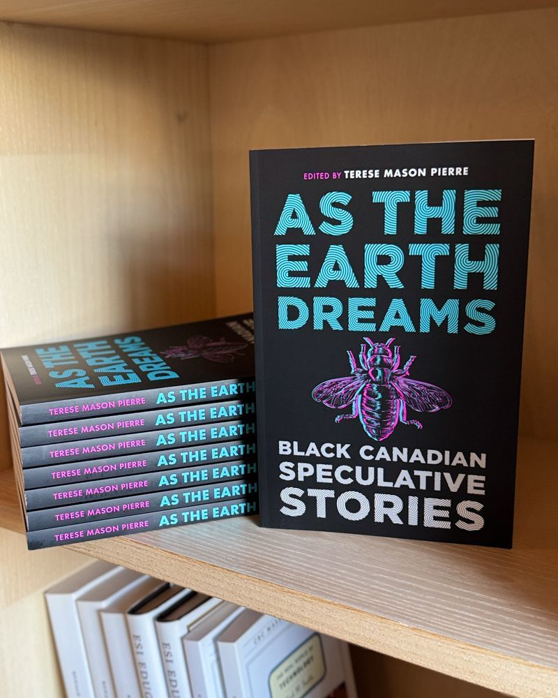 A stack of the book AS THE EARTH DREAMS: BLACK CANADIAN SPECULATIVE STORIES sits on a wooden bookshelf beside a standing copy that displays the cover. The cover features bold blue text with a vibrant illustrated bug on a black background.