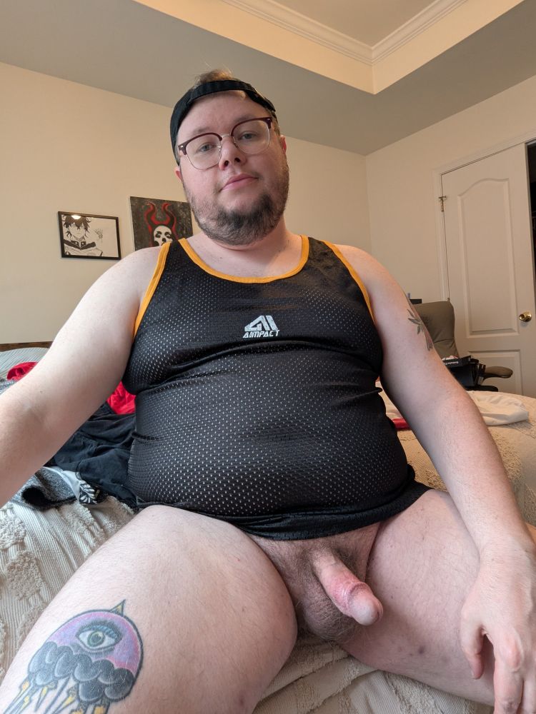 Me sitting with just a tank top and baseball cap on with my cock exposed.