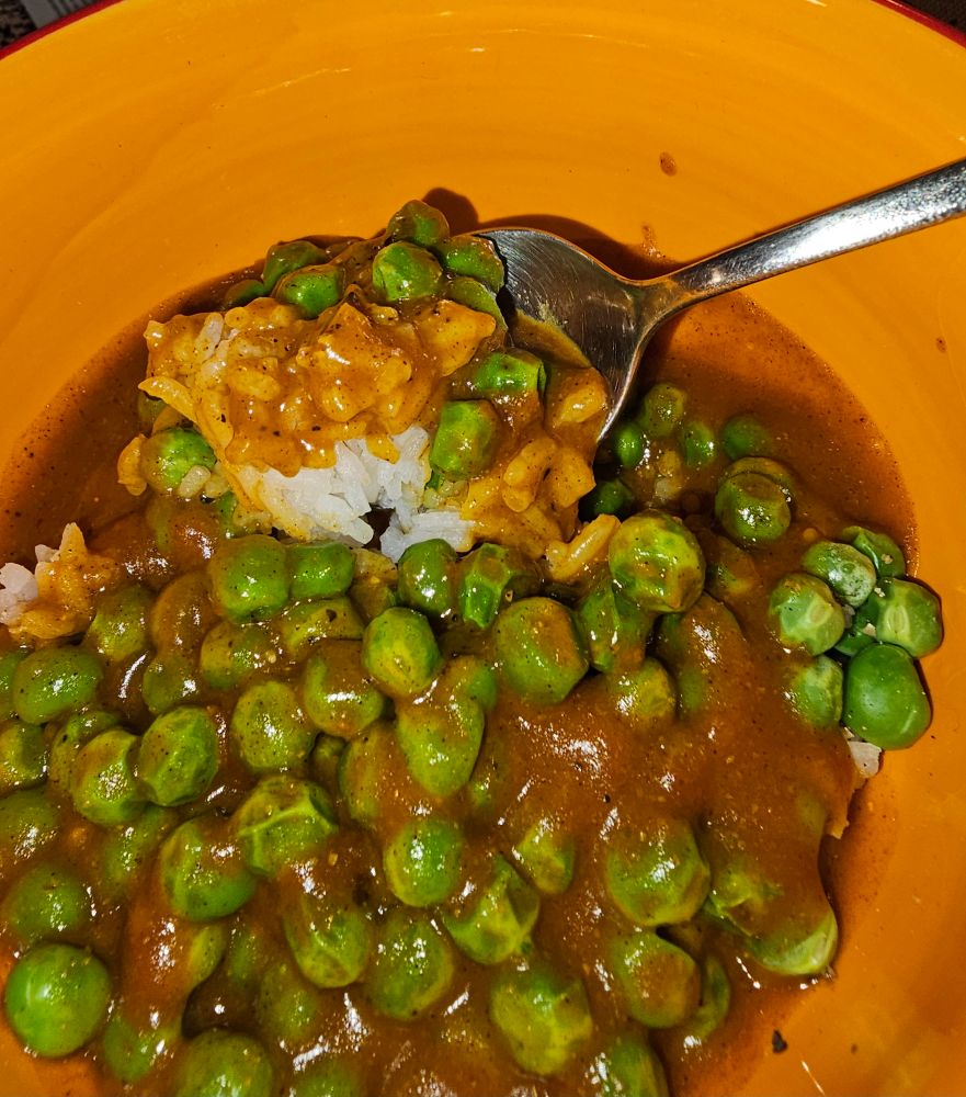 A photo of a bowl full of white rice and green peas covered in McDonnells curry sauce that I doctored up a little with cayenne pepper and curry powder.