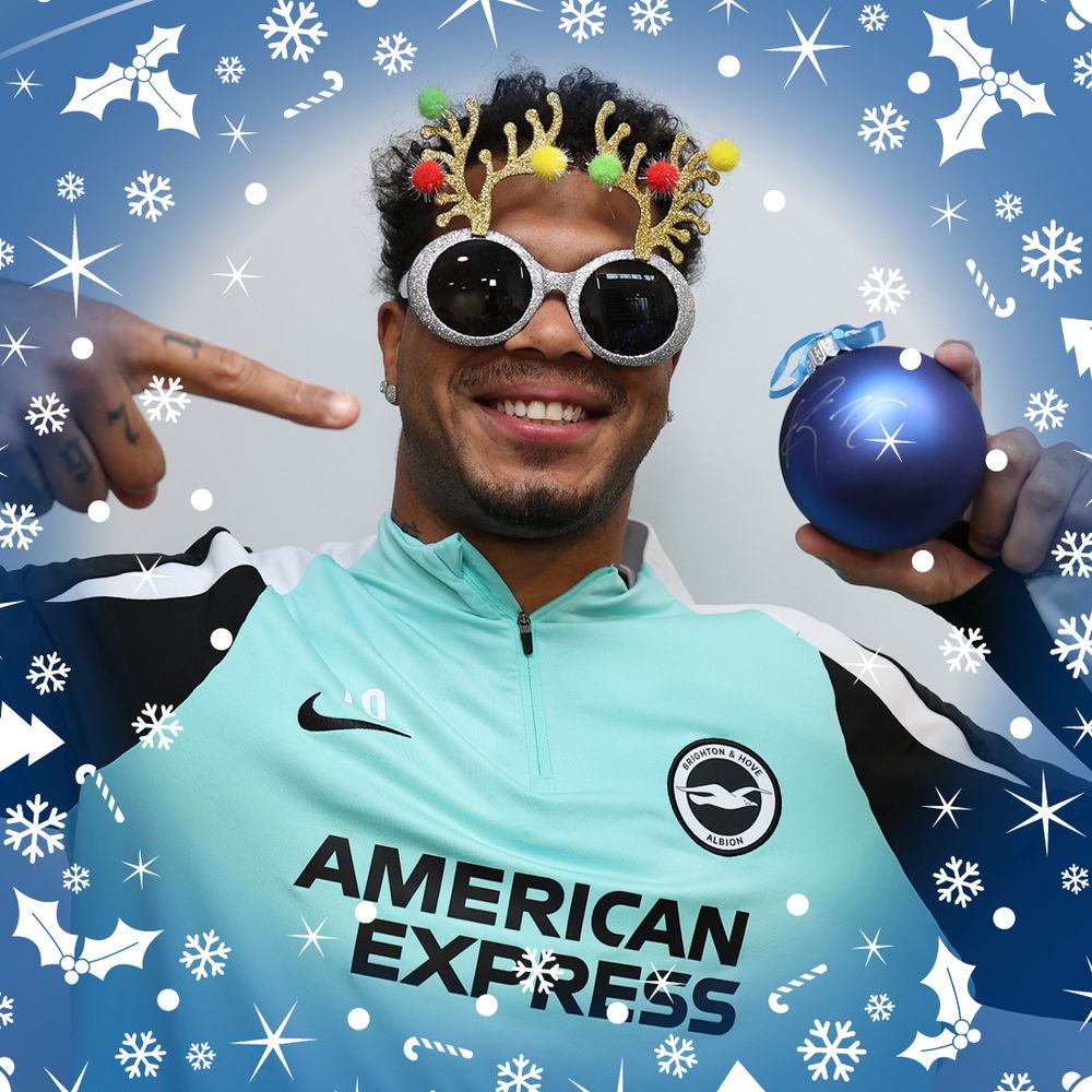 Georgi, with a festive pair of reindeer sunglasses gives a big smile and point to his signed bauble