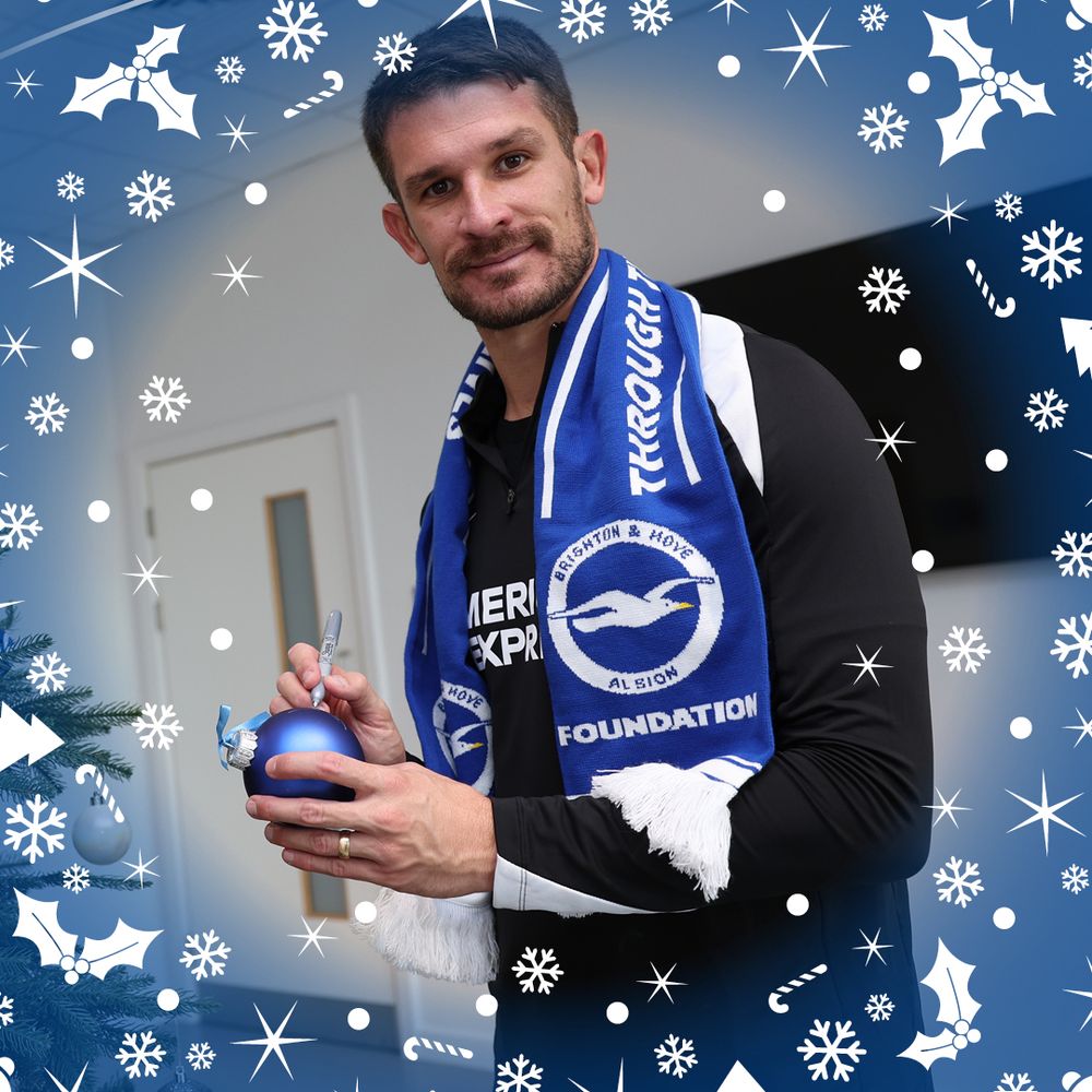 Dario, stood wearing a Foundation scarf smiles to camera while signing his bauble