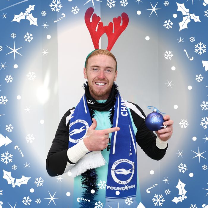 A reindeer-eared Jason Steele gives a big smile and a point to his signed festive decoration