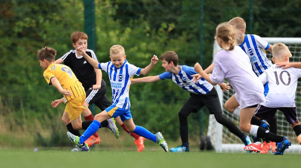 A warm-up game of tag has participants in Brighton kits laughing