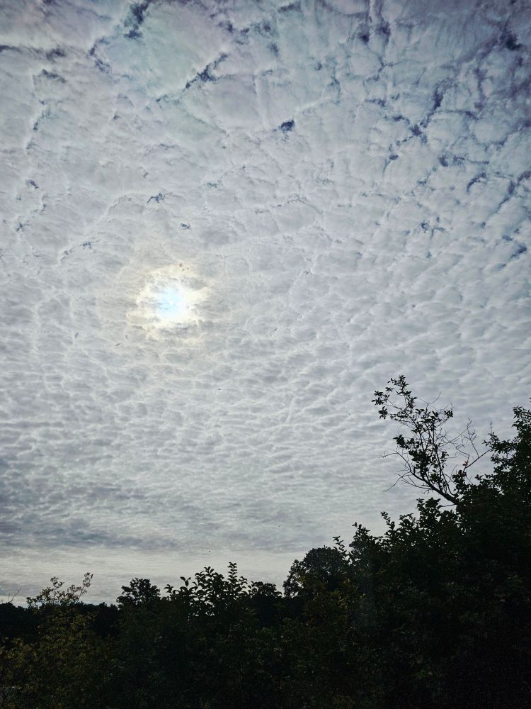 Dichte Bewölkung mit einem Loch mittendrin, durch das man den blauen Himmel sehen kann.